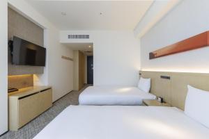 a hotel room with two beds and a tv at JR Kyushu Hotel Blossom Shinjuku in Tokyo