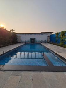 a large swimming pool with the sun setting in the background at Windchime Cottages in Alibaug