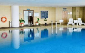 una piscina en un hotel con sillas y mesas en Georgetown near Gurney and Straits Quay Seaview with Netflix and Washer Dryer, en George Town