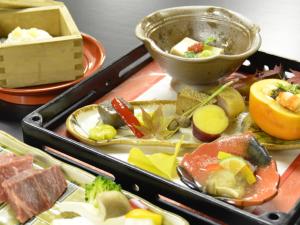 ein Tablett mit verschiedenen Arten von Lebensmitteln auf einem Tisch in der Unterkunft Kadonobo Ryokan in Kōbe