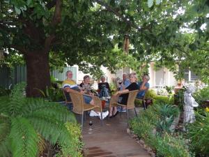 un grupo de personas sentadas en sillas bajo un árbol en Hahndorf Oak Tree Cottages, en Hahndorf