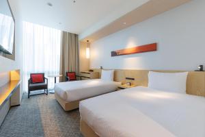 a hotel room with two beds and a chair at JR Kyushu Hotel Blossom Shinjuku in Tokyo