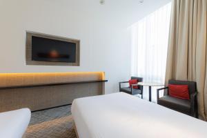 a hotel room with a bed and a tv at JR Kyushu Hotel Blossom Shinjuku in Tokyo