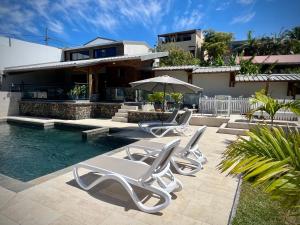 a group of white chairs and an umbrella next to a pool at La Caze Grande Anse in Petite Île