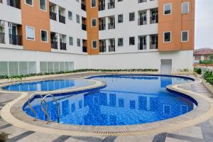 a swimming pool in front of a building at Homey 2BR Apartment at Urban Heights Residence By Travelio in Tangerang