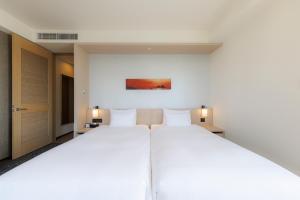 a large white bed in a room with two lamps at JR Kyushu Hotel Blossom Shinjuku in Tokyo