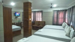a hotel room with two beds and a television at Royal Residency Payyanur in Payyannūr +5 photos