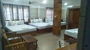a room with two beds and a table and chairs at Royal Residency Payyanur in Payyannūr