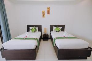 two beds in a room with white walls at Monaburi Boutique Resort in Rawai Beach