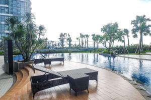 a patio with a table and benches next to a pool at Best Choice and Comfortable Living 2BR at Anderson Supermall Mansion Apartment By Travelio in Surabaya