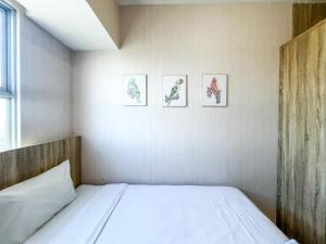 a bedroom with three pictures on the wall at Best Choice and Comfortable Living 2BR at Anderson Supermall Mansion Apartment By Travelio in Surabaya +14 photos