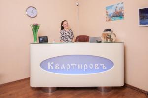 una mujer de pie detrás de una recepción en una habitación en Kvartirov Apartments City, en Krasnoyarsk