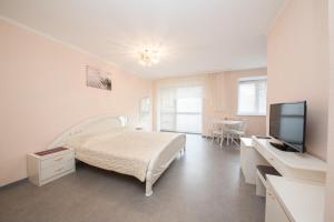 a white bedroom with a bed and a television at Kvartirov Apartments City in Krasnoyarsk