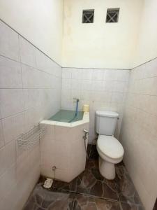 a bathroom with a toilet and a bath tub at De Monjali Homestay Jogja in Kejayan