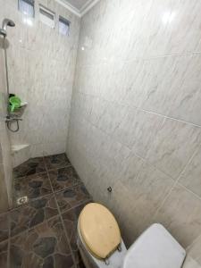 a bathroom with a toilet and a tiled wall at De Monjali Homestay Jogja in Kejayan +9 photos