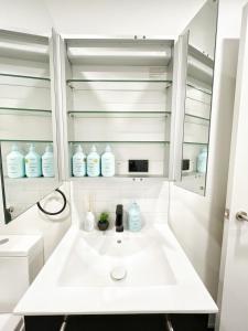 a white bathroom with a sink and a mirror at Serene Cityscape 1B Apt Near Skytower vs Gym Pool Sauna in Auckland