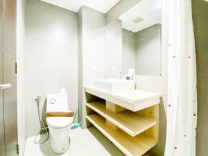 a bathroom with a toilet and a sink and a mirror at Good and Restful Studio at Patraland Amarta Apartment By Travelio in Kejayan +1 photo