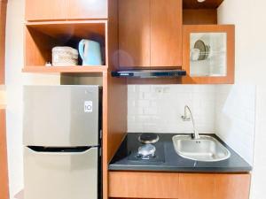 a small kitchen with a sink and a refrigerator at Good and Restful Studio at Patraland Amarta Apartment By Travelio in Kejayan