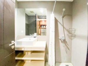 a bathroom with a white sink and a mirror at Good and Restful Studio at Patraland Amarta Apartment By Travelio in Kejayan