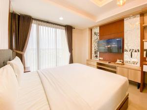 a bedroom with a large white bed and a television at Good and Restful Studio at Patraland Amarta Apartment By Travelio in Kejayan