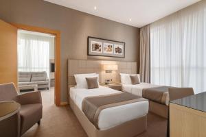 a hotel room with two beds and a couch at TRYP by Wyndham Abu Dhabi City Center in Abu Dhabi