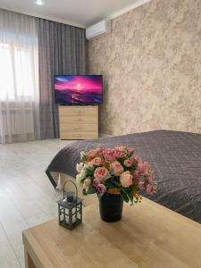a bedroom with a bed with a vase of flowers at Однокомнатная студия, центр города in Kostanay