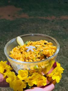 a person holding a bowl filled with yellow flowers at Aranya Stuga Pushkar in Ajmer