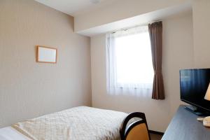 a bedroom with a bed and a desk with a television at Hotel Ocean Iwasawa in Hirono
