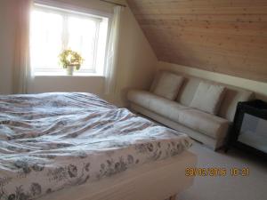 a bedroom with a bed and a couch and a window at Bakkegården Homestay in Spottrup