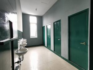 a bathroom with three sinks and green doors at Populair Hostel Braga in Bandung
