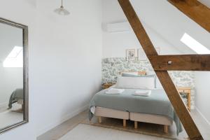 ein Schlafzimmer mit einem Bett und einem Spiegel in der Unterkunft Maison Morny Your Exquisite Retreat near Deauville in Cricquebœuf + 20 Fotos