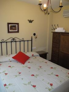 Un dormitorio con una cama con una almohada roja. en Apartamentos Valle del Guadalquivir, en Arroyo Frío