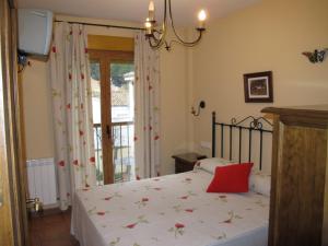 Un dormitorio con una cama con una almohada roja. en Apartamentos Valle del Guadalquivir, en Arroyo Frío