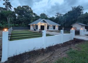 a white fence in front of a house with lights at Mar'wanis Villa Homestay Beaufort Sabah in Bambangan
