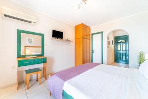 a bedroom with a bed and a desk and a television at Spyridoula Studio 13 in Paleokastritsa