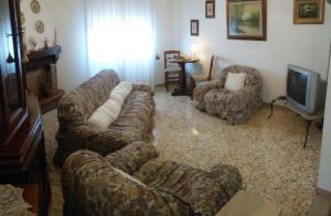 a living room with a couch and chairs and a television at Apartment Nonna Cucca in Cecina
