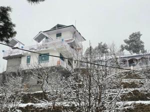 a house on a hill with snow on it at Kin Vatika Homestay in Kalpa
