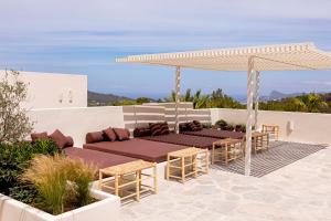 a patio with tables and chairs under a white umbrella at Boutique Hotel Jardines de Palerm in San Jose
