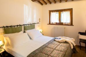 a bedroom with a bed with white sheets and a window at appartamenti vacanza antica mattonata in Stazione di Assisi