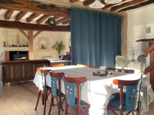 a kitchen with a table with chairs and a blue curtain at Gîte Nature la Carillonnerie in Bossay-sur-Claise