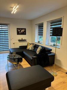 a living room with a black couch and a table at FeWo Wiehl-Marienhagen, Modern, ruhig, ländlich in Wiehl