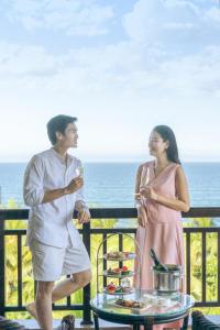 a man and a woman standing on a balcony with wine glasses at Danang Marriott Resort & Spa in Danang