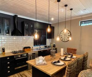 eine Küche mit einem Tisch und einer Uhr an der Wand in der Unterkunft The Porcupine Porch in Marloth Park