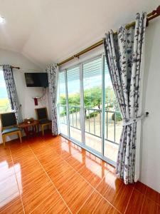 Maingern Maithong Resort في سارابوري: غرفة معيشة مع نافذة كبيرة وأرضية خشبية