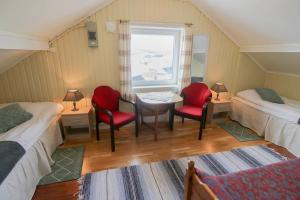 a room with two beds and a table and chairs at Hedvig Guesthouse & Ragnahus in Bugøynes