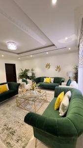 una sala de estar con sofás verdes y almohadas amarillas. en شقة غرفتين نوم وصالة وحديقة خارجية, en Riad