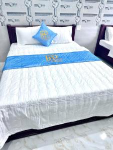 a large white bed with blue pillows on it at Hotel PHƯƠNG HOA in Phù Cát