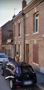 Czarny samochód zaparkowany przed ceglanym budynkiem w obiekcie L'artistique, 4 lits, 2 chambres, stationnement gratuit, spacieux, atypique w Amiens