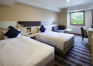 a hotel room with two beds and a chair at Yumoto Fujiya Hotel in Hakone