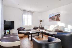 ein Wohnzimmer mit Sofa und Fernseher in der Unterkunft 240m des plages - Maison avec jardin pour 12 in La Guérinière